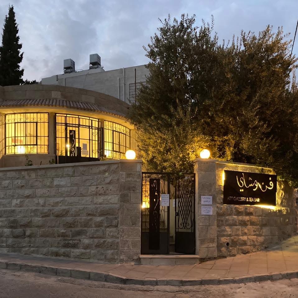 The stone corner house of Fann wa Chai art gallery and tea bar glowing warmly at dusk in Jabal Al Weibdeh, Amman