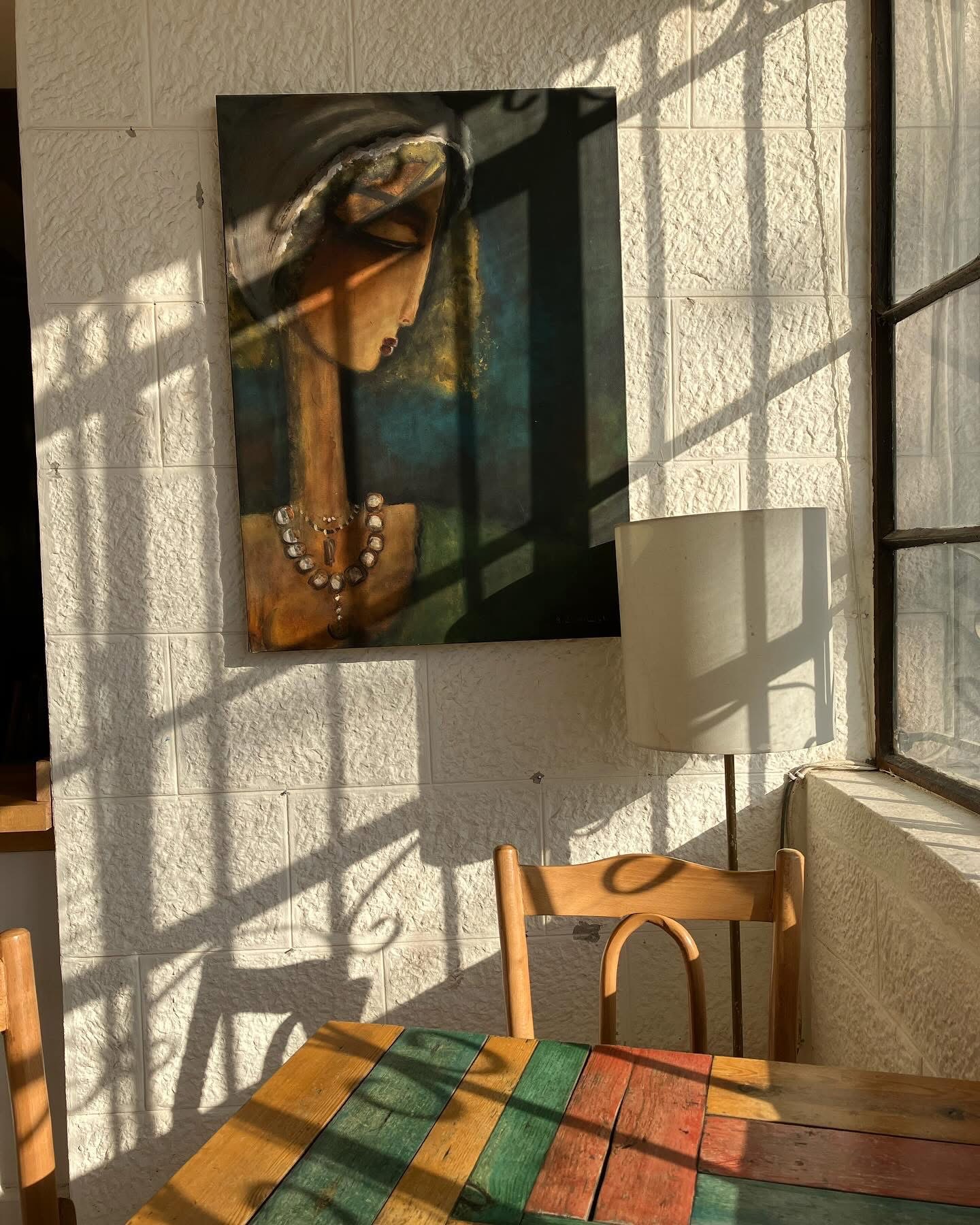 Afternoon light and window-grille shadows moving across a portrait painting of a woman on a white stone wall at Fann wa Chai